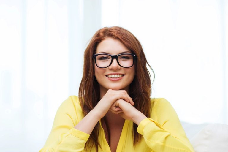 Smiling woman in glasses wearing a yellow shirt, showcasing confidence and positivity, symbolizing a positive mindset change