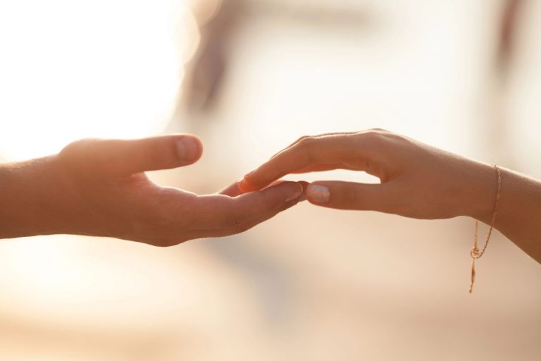 Two hands are reaching towards each other with fingertips touching, set against a softly blurred, light background—a gentle reminder that lack of boundaries weaken relationships.